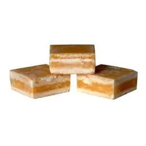 Three layered caramel and vanilla square desserts.