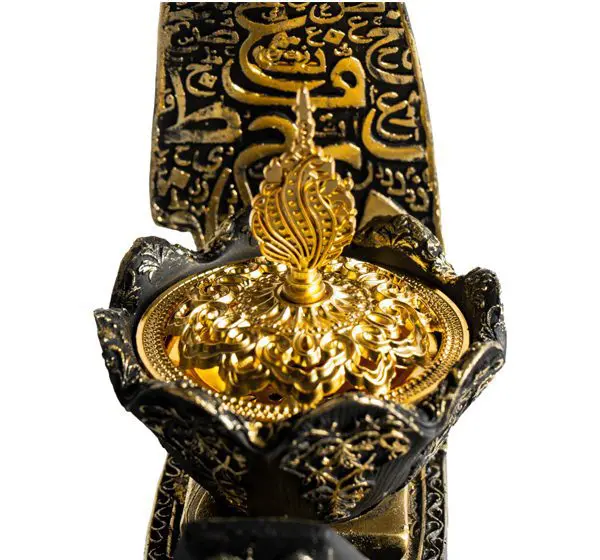 Intricately designed gold and black ornamental buckle with Arabic calligraphy.